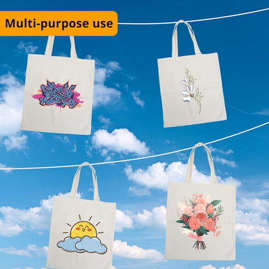 Four tote bags with designs hanging against a blue sky.
