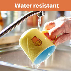 Yellow mug with blue interior being rinsed under running water, labeled 'Water resistant'.